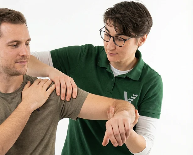 Physiotherapeutin behandelt die Schulter eines Patienten
